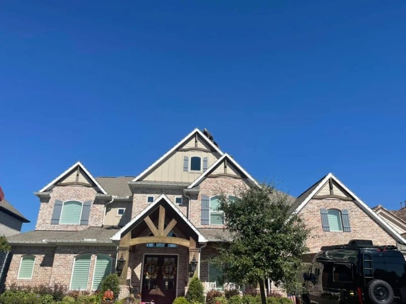 Installer on a roof hanging Christmas lights by hand