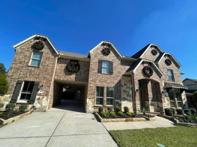 Large house photographed in daylight with lights and wreaths installed
