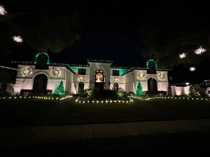 Large house with six rooflines each outlined in Christmas lights
