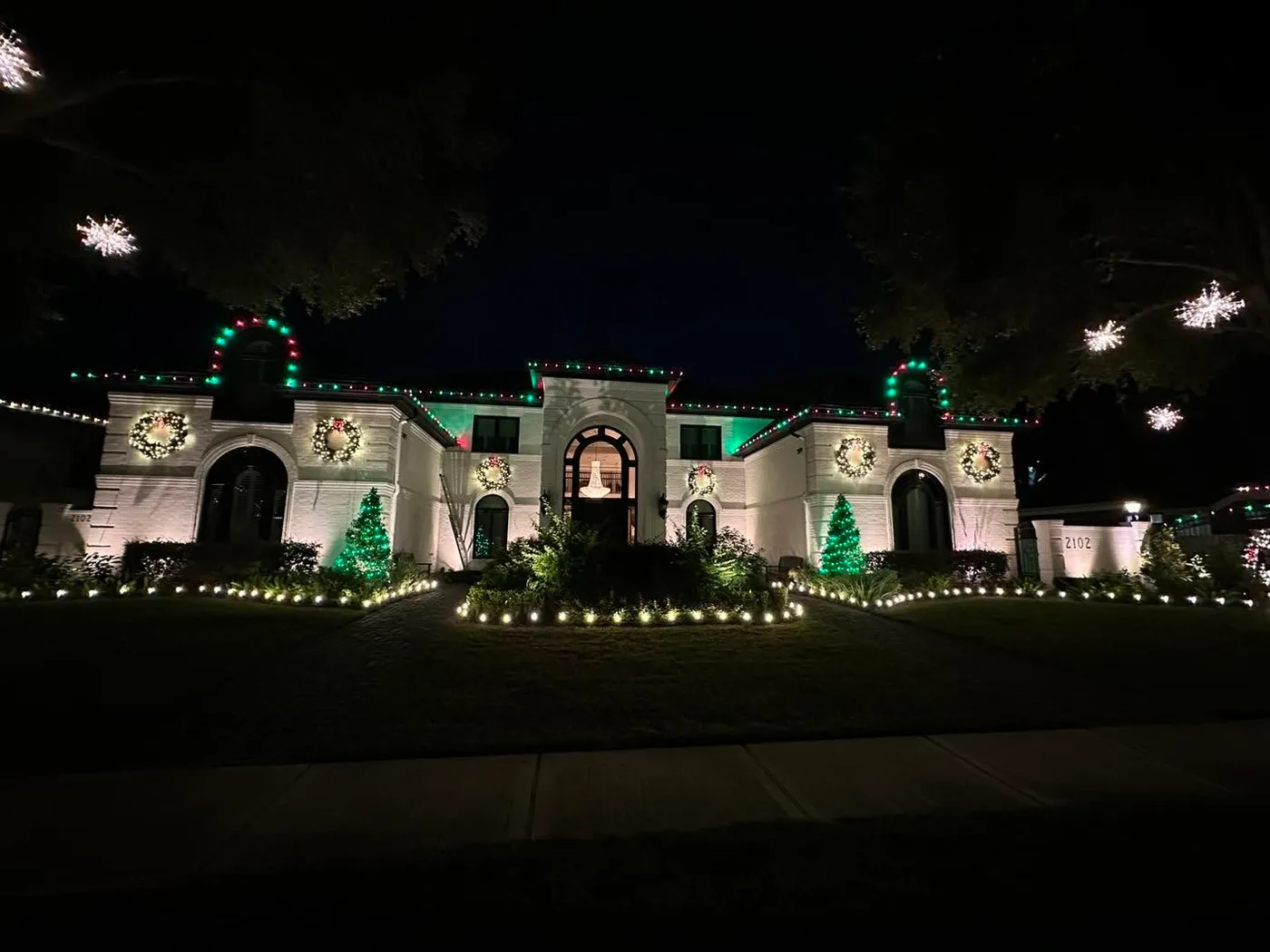 Large house with six roofs and the roofline wrapped in Christmas lights