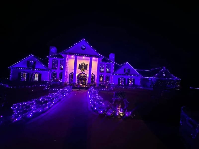 Palatial estate outlined in Christmas lights with purple accent lighting