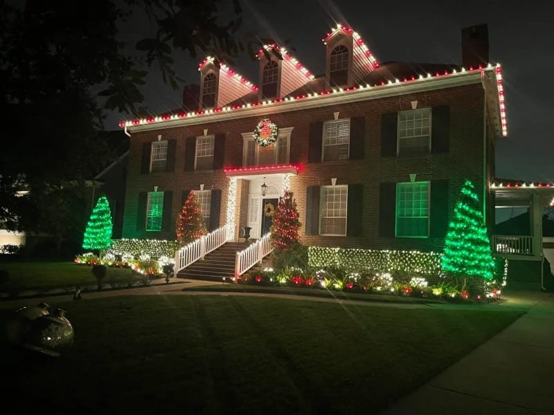 Two-story colonial house with three gables, rooflines and landscaping all lit